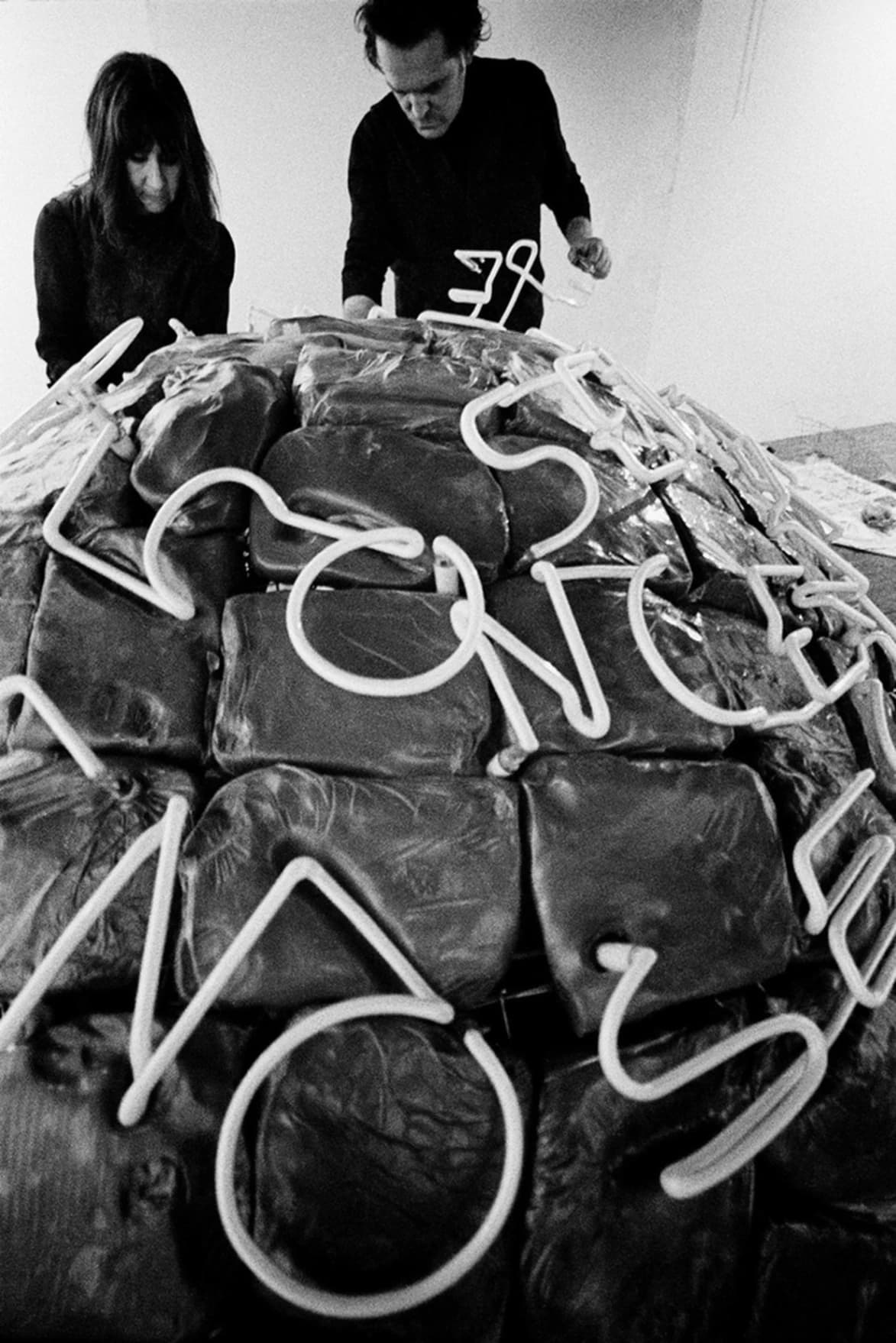 Marisa e Mario Merz di fronte all'opera di Mario "Se il nemico si concentra perde terreno, se si disperde perde forza" , Galleria Arco d'Alibert, Roma (marzo 1968). Foto di Claudio Abate.